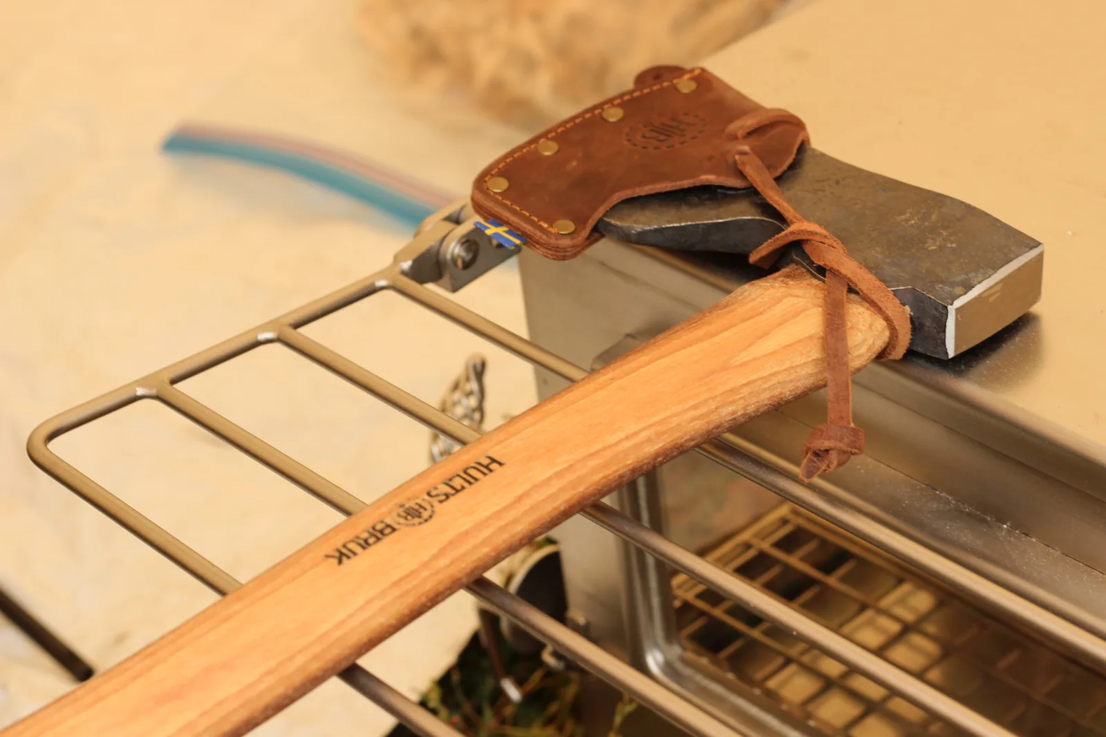 The Hults Bruk Dvärdala hunting axe in its leather sheath resting across the stove's side rack