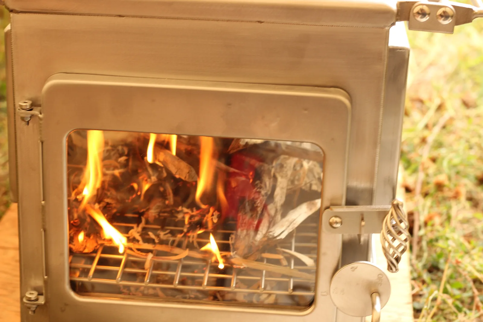 First flames visible through the front glass of the stove as the shavings catch