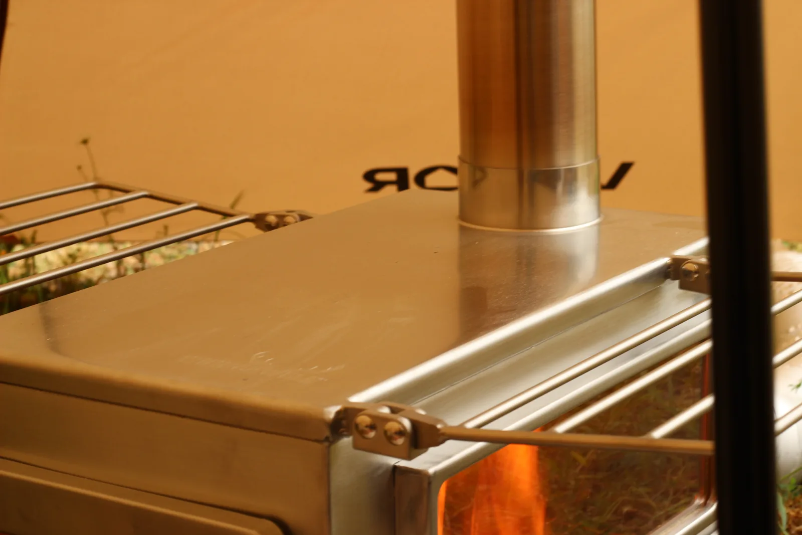 The stove top plate and chimney base photographed while the stove is running, with the tent behind