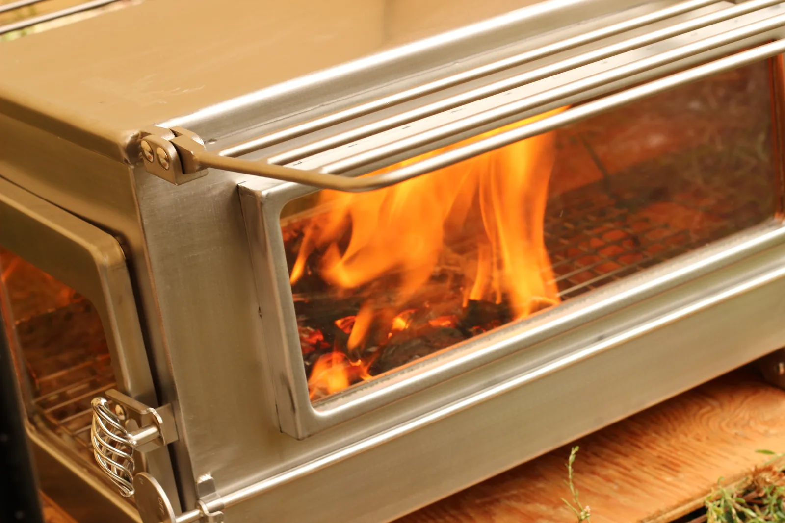 The long side window filled with tall flame at full burn rate, the stove body brightly lit